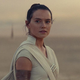 Daisy Ridley stands on a desert in costume as her character in Star Wars.